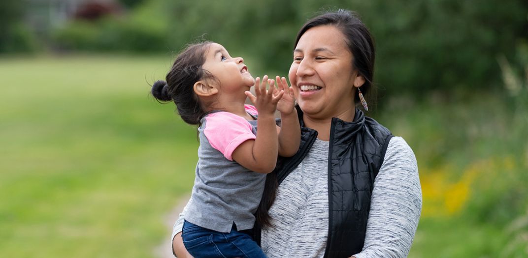 A mother holding her little girl in her arms as they both smile.