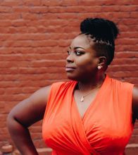 An African American woman standing with her hands on her hips looking away from the camera