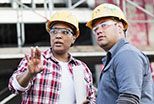 Two  construction workers looking at a project on a building site.