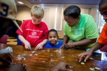 A woman helping two boys complete a puzzle