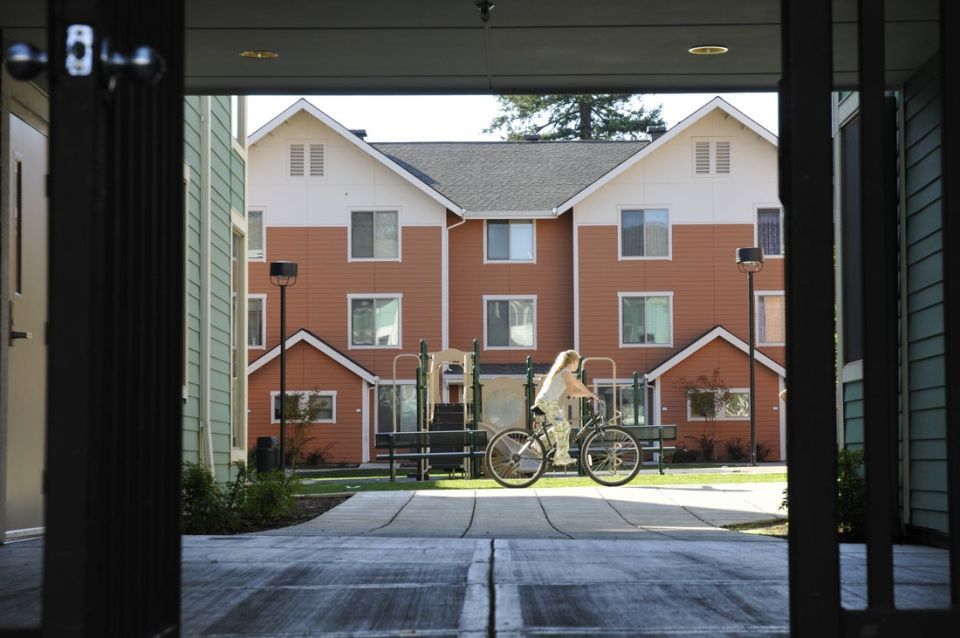 view from inside of a building looking out at a child on a bike riding on a community sidewalk