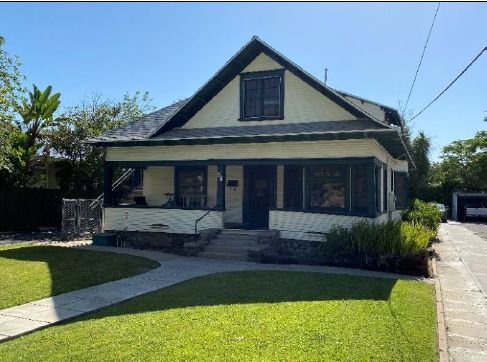 Yellowish bungalow home trimmed in dark green