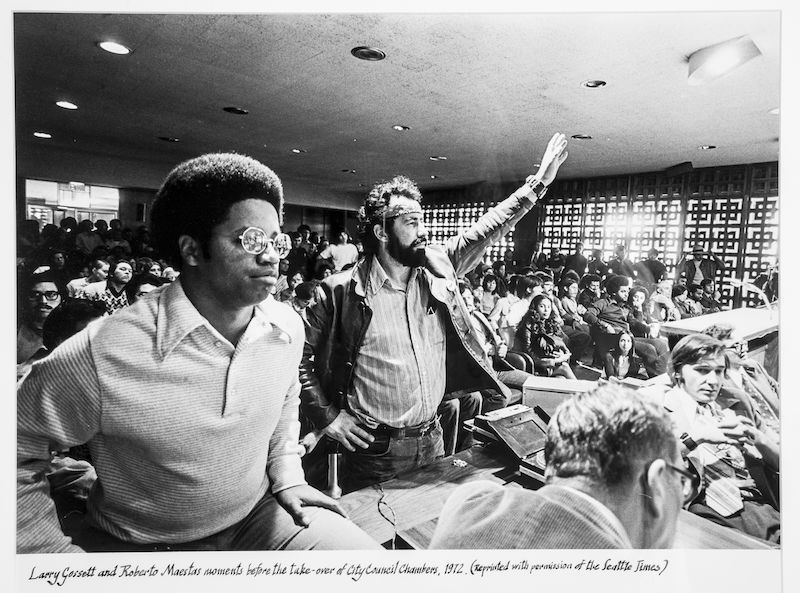 Black-and-white photo of two men standing and speaking