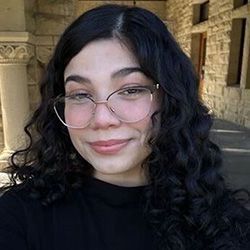 Smiling woman wearing glasses with shoulder length black hair and black sweater