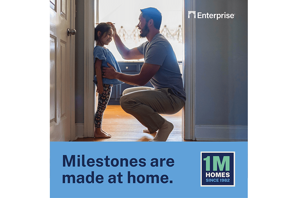 A father kneels to measure the height of his child at a doorway with the text printed below - "Milestones are made at home. 1M homes since 1982."