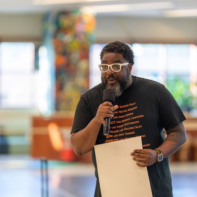 A man speaking in a microphone and holding a piece of paper