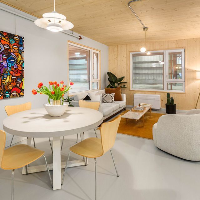 A dining room and living room with a white dining table and yellow chairs