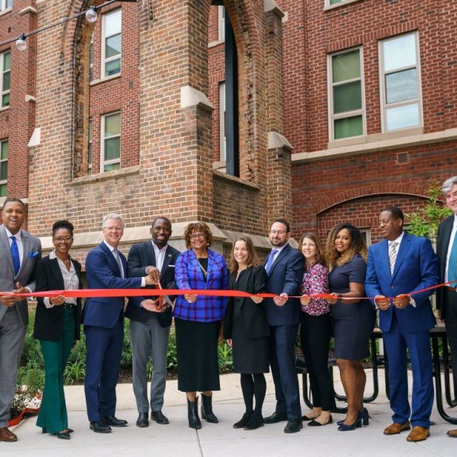 Smiling people in business suits cutting red ribbon