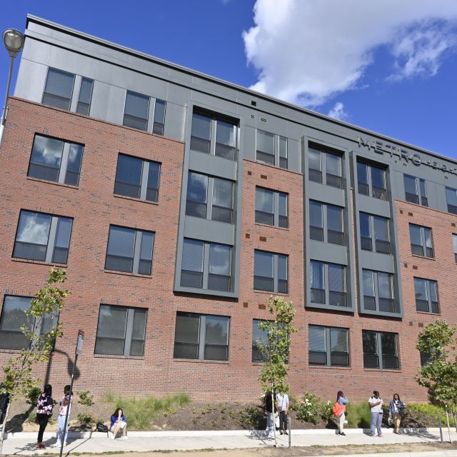 Four-story brick multifamily housing building with blue sky in the background