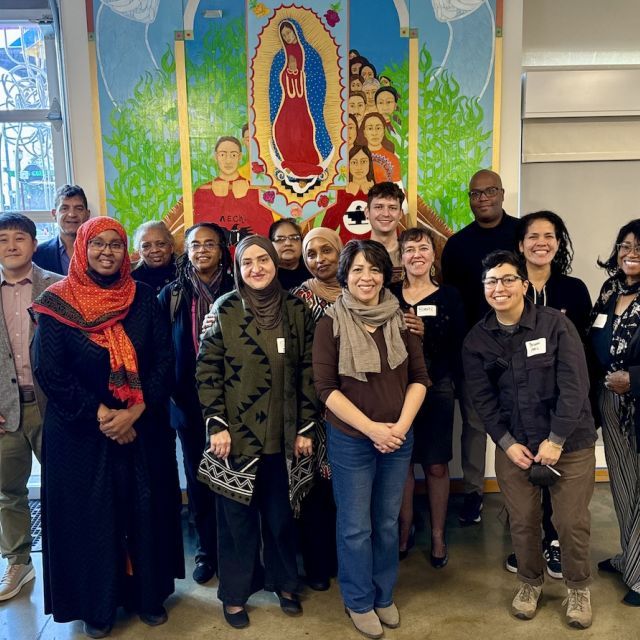 Group of smiling people standing in front of colorful mural